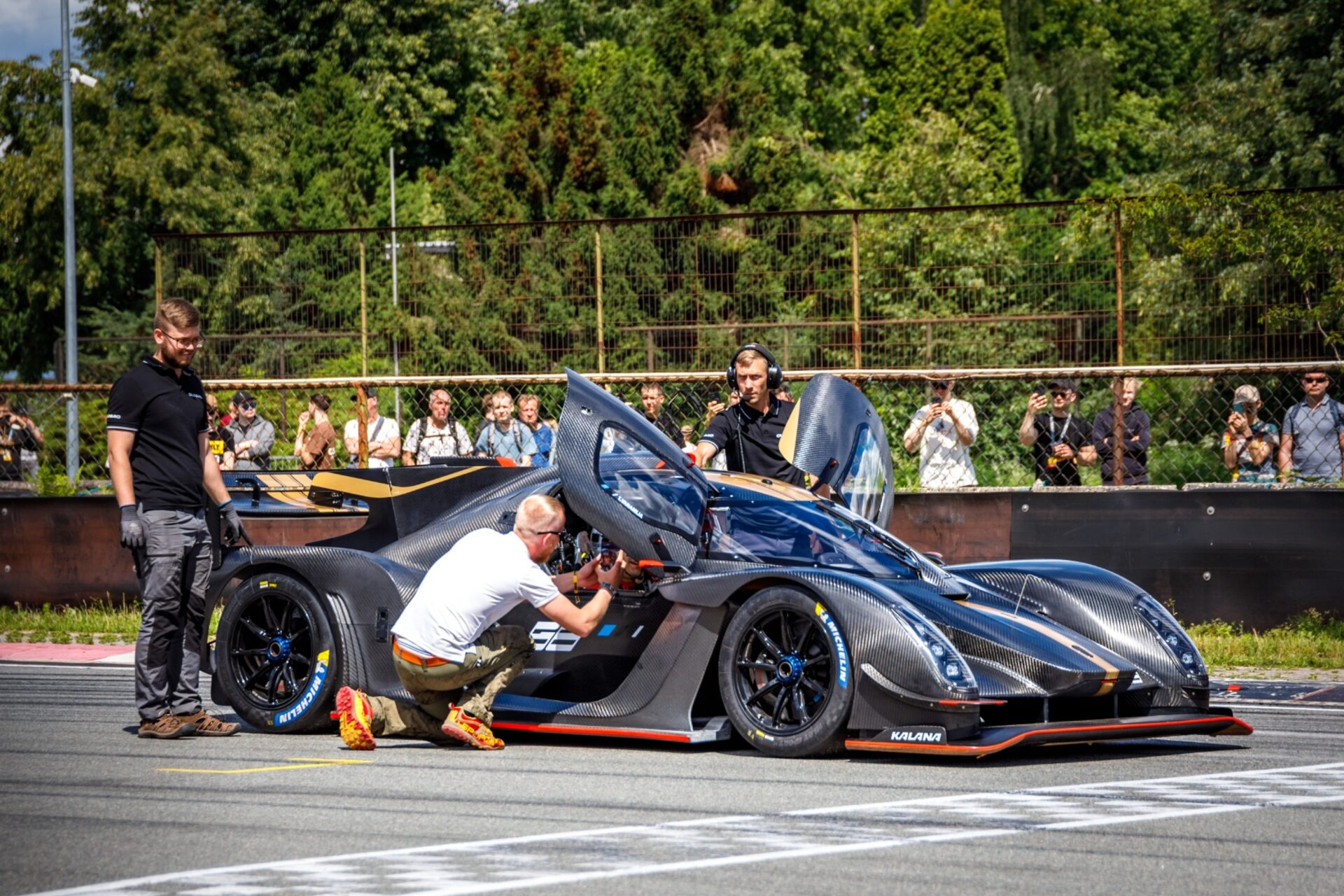 Team and spectators surrounding Kalana in the pitlane after the record lap at Bikernieki